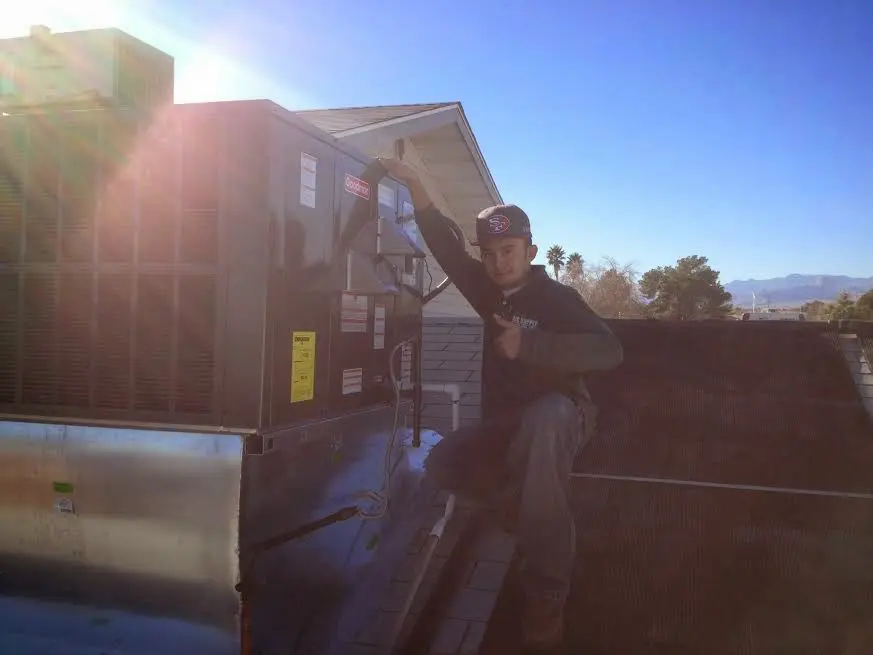 HVAC technician performing AC Tune-Up on a rooftop unit in Dumbarton